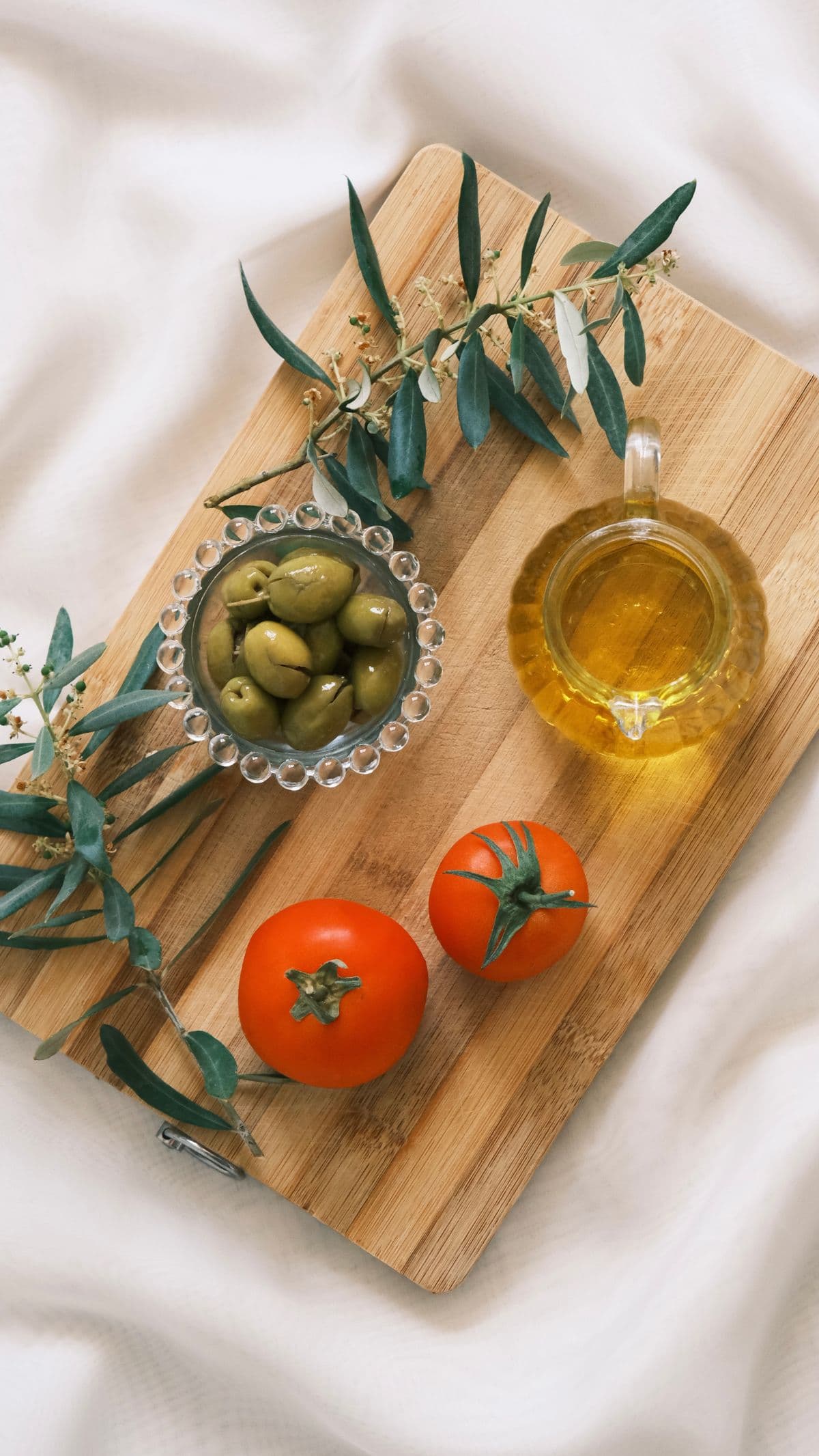 Whole-food ingredients — olive oil, tomatoes and olives on a wooden board